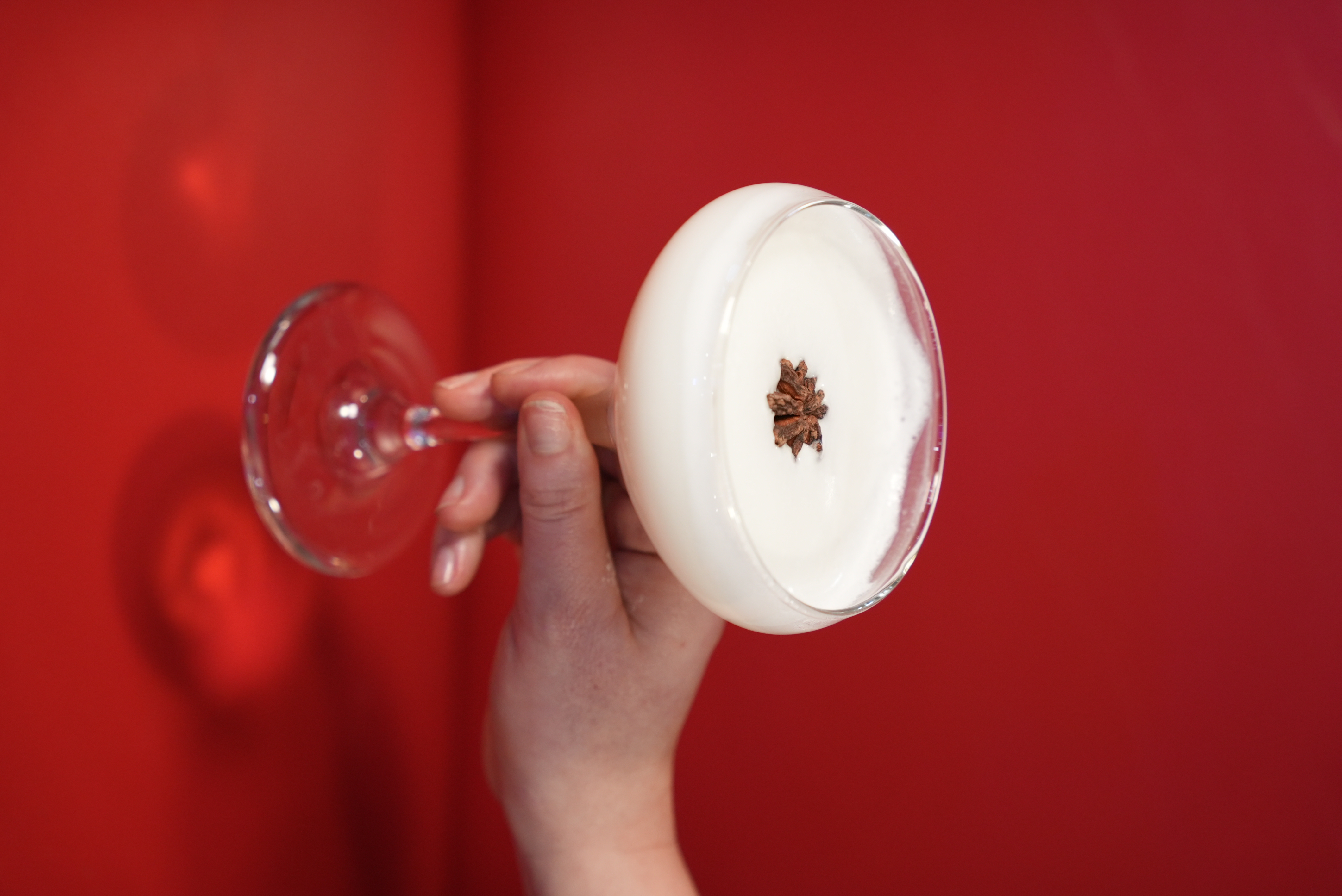 a hand holding a glass of white liquid
