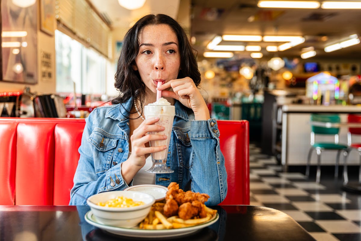 Girl drinking milkshake and eating chicken tenders