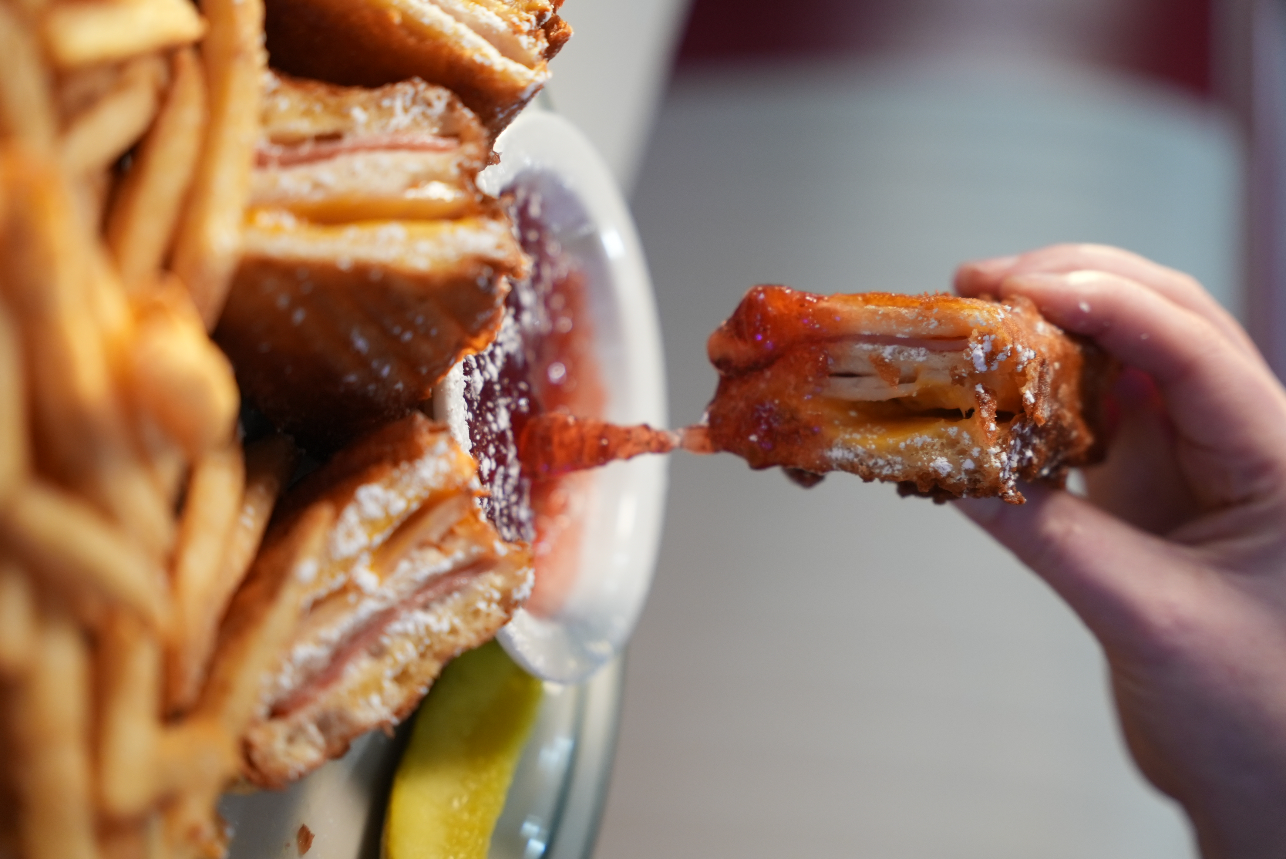 a hand dipping a piece of food into a plate
