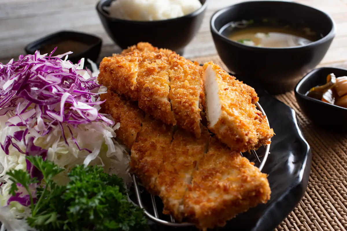 two fried pieces of Japanese food with dipping sauces