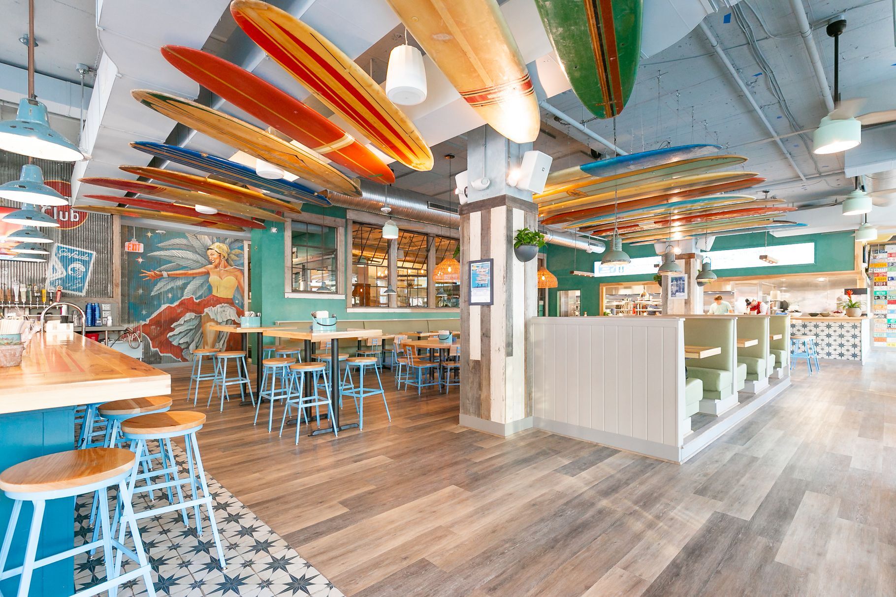 a room with tables and chairs and surfboards from ceiling
