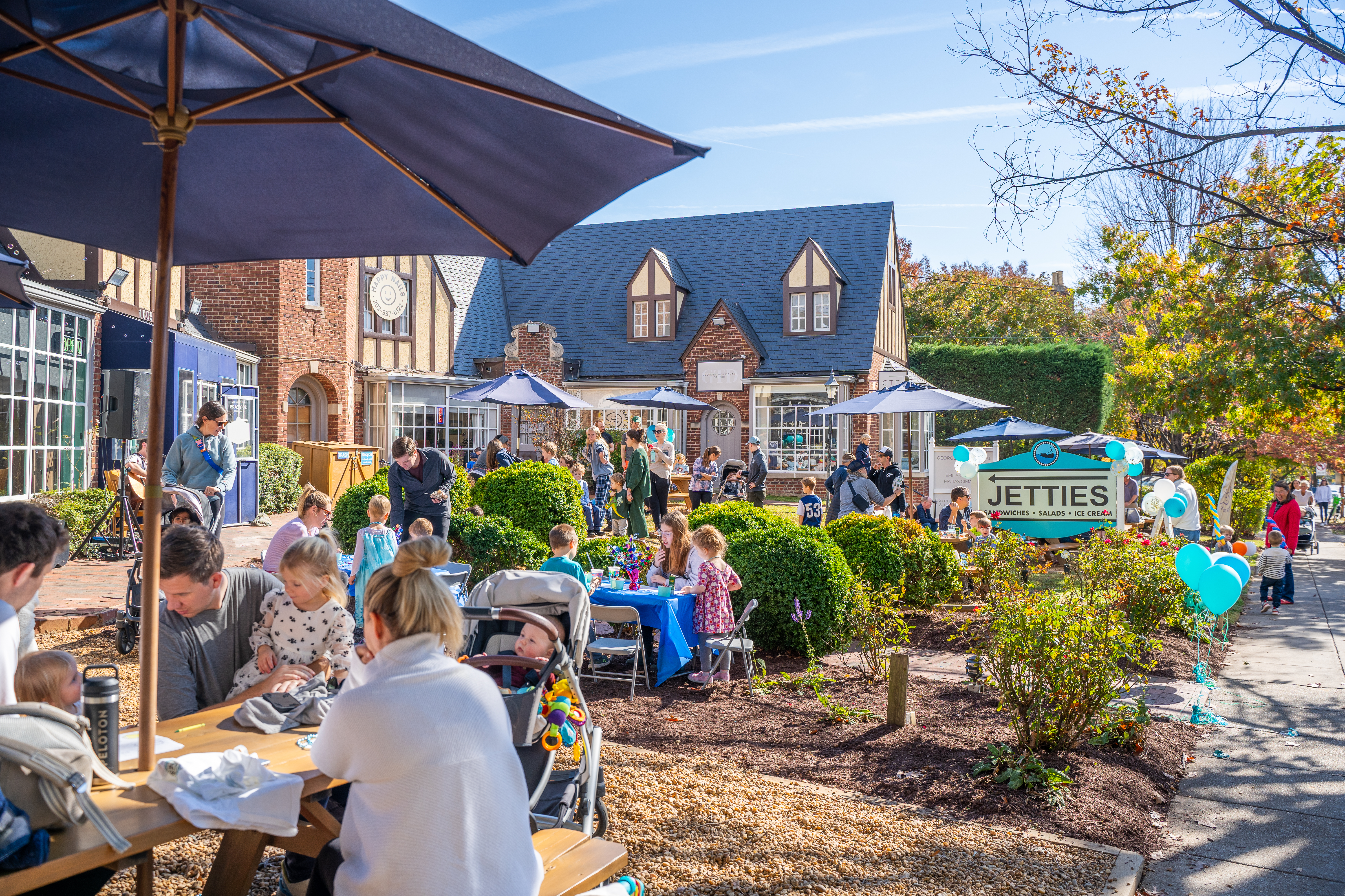 a group of people outside with umbrellas and tables and chairs