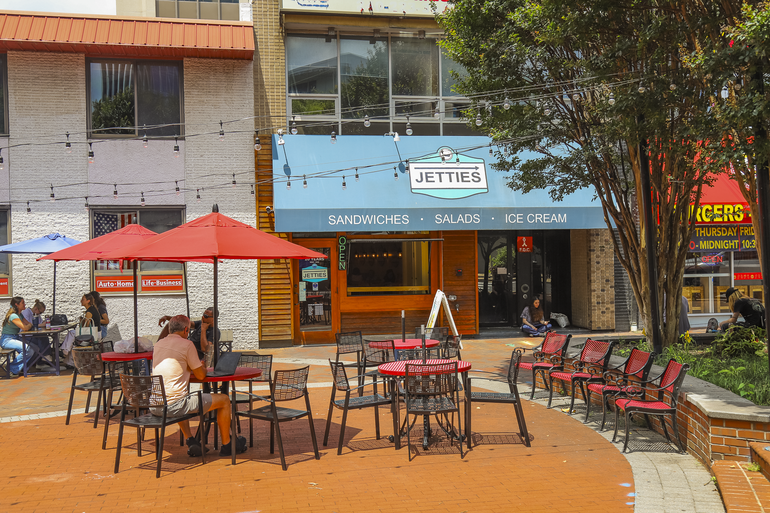 Tables with umbrellas on a patio in front of a Jetties