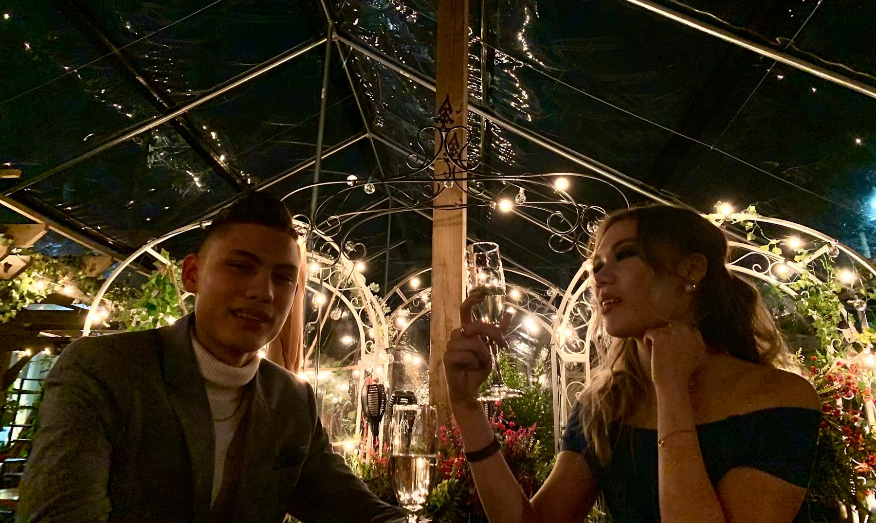 a person holding a wine glass standing next to a christmas tree