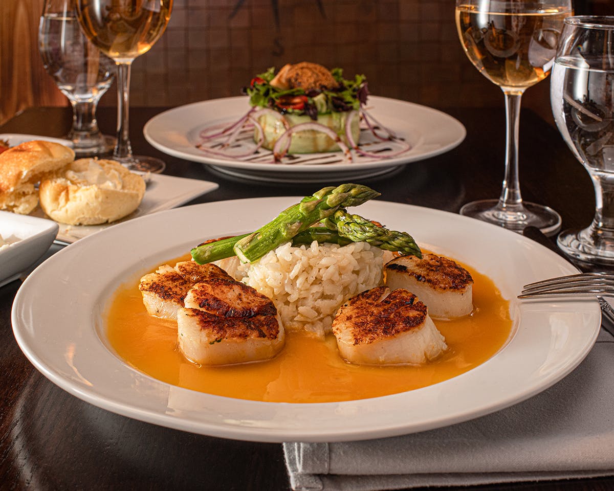 a plate of food and glasses of wine on a table