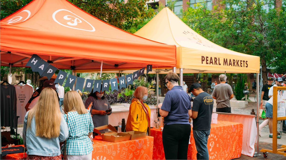 a group of people standing next to an orange umbrella