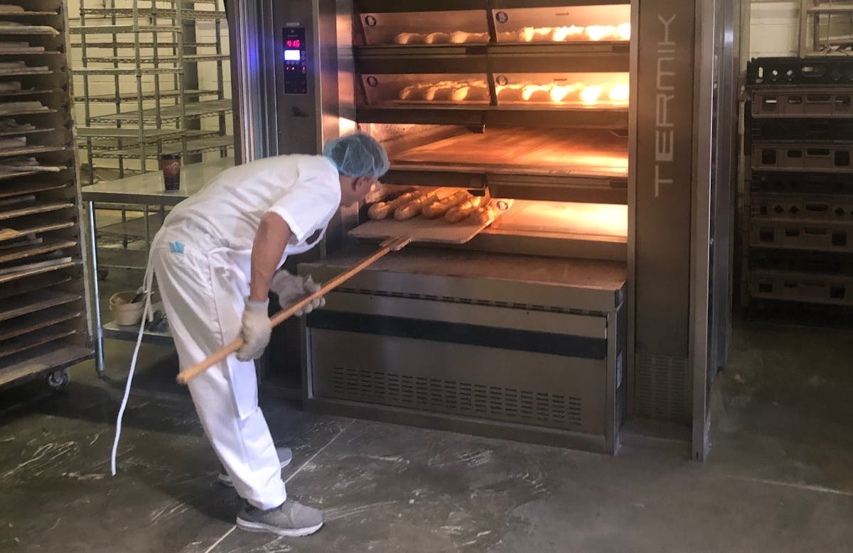 a man putting bread in an oven