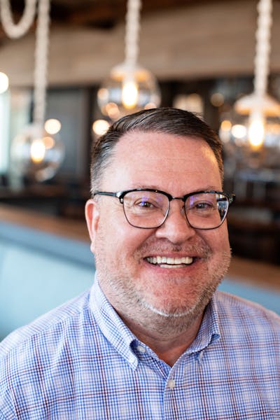 a man wearing glasses and smiling at the camera