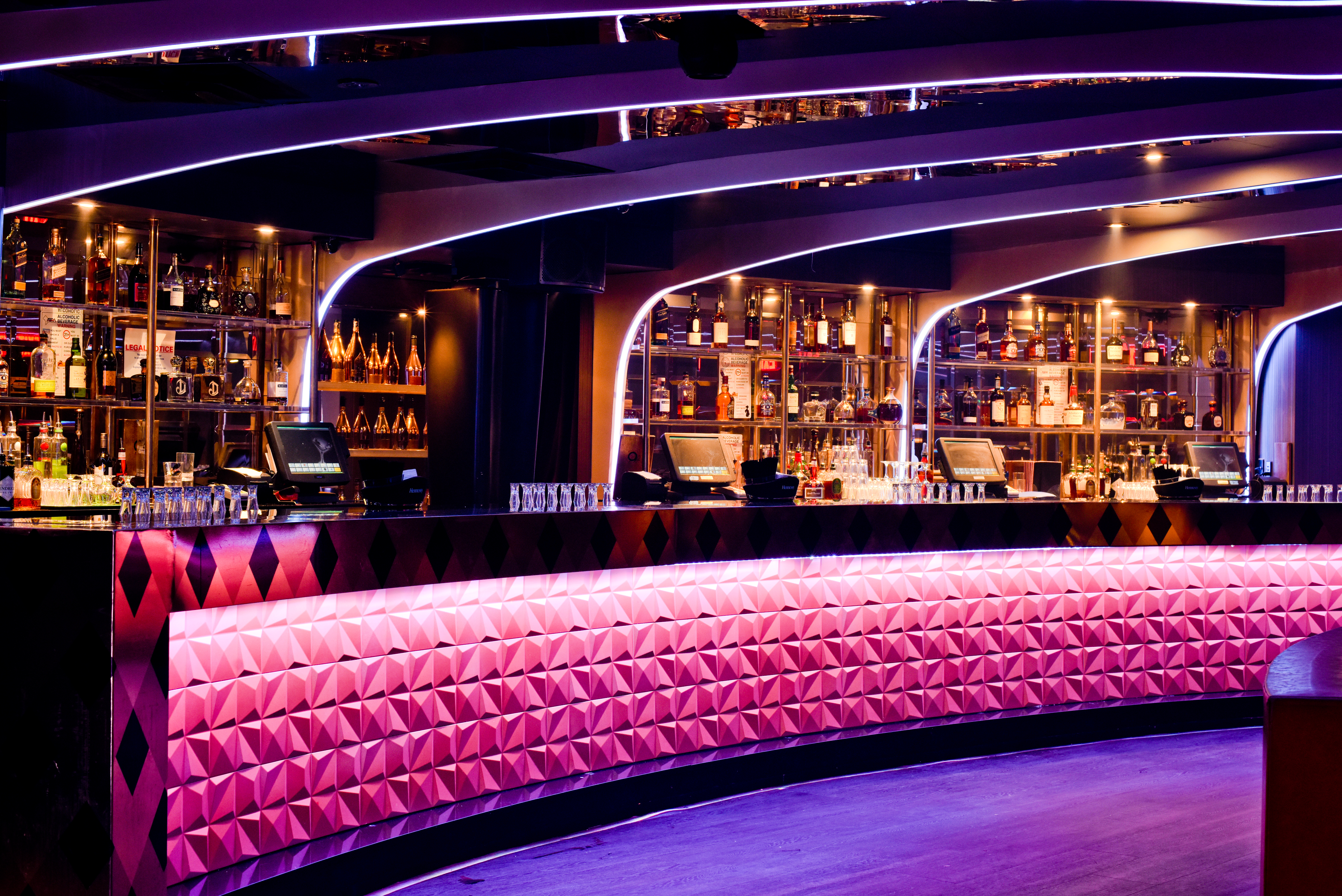 a bar with a pink wall and bottles