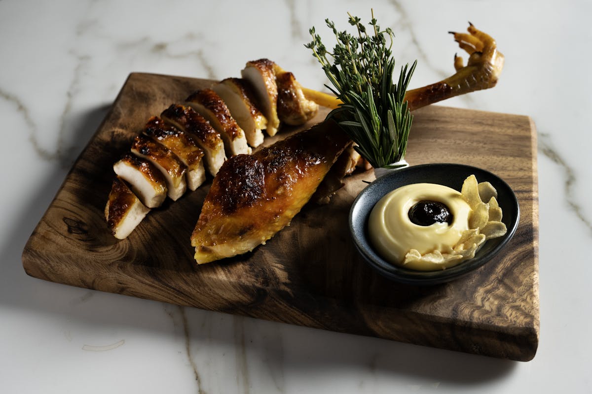 sliced chicken with a yellow aioli and herbs.