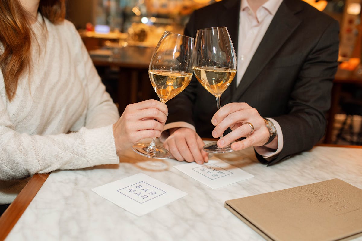 a person sitting at a table with wine glasses
