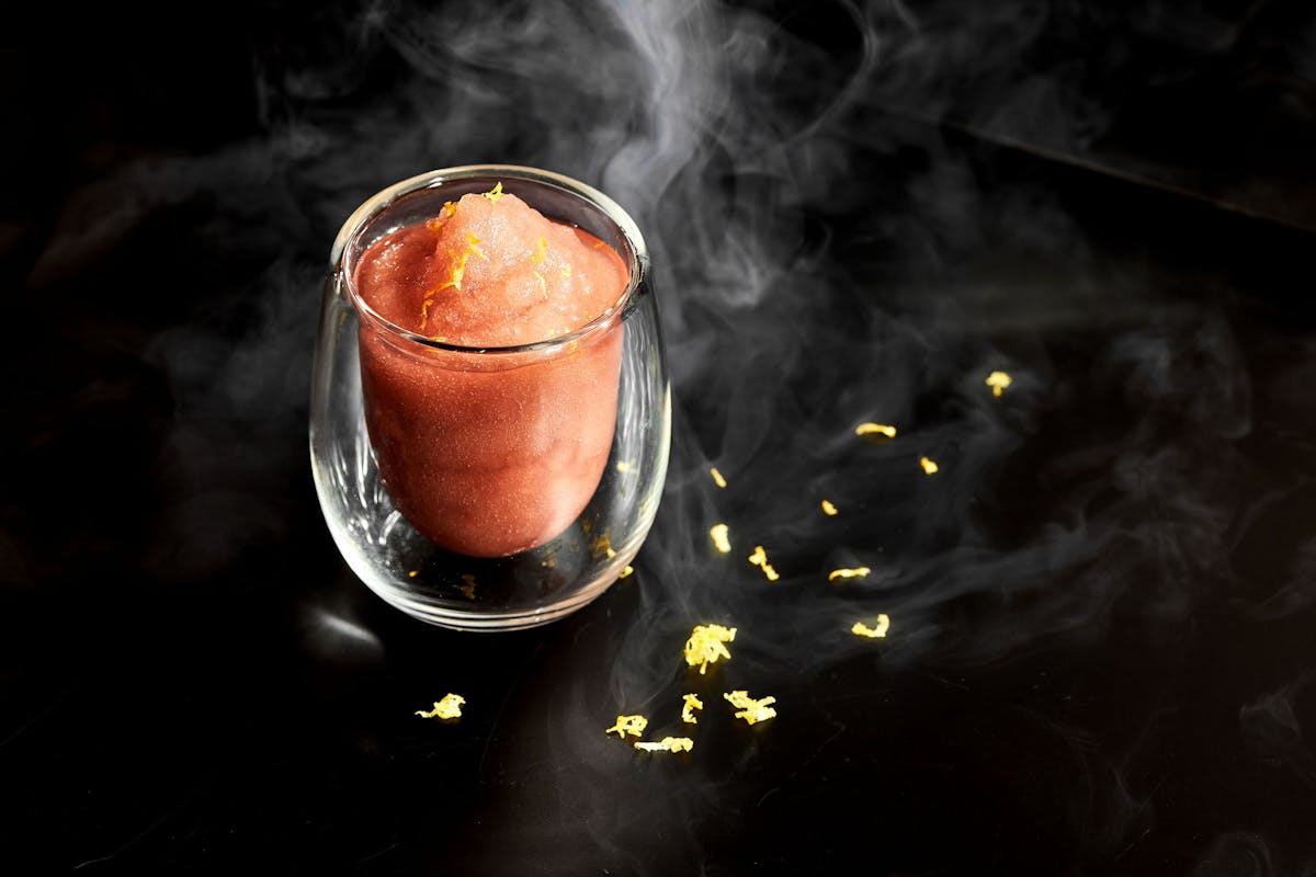 a close up shot of a frozen red beverage surrounded by gold flakes