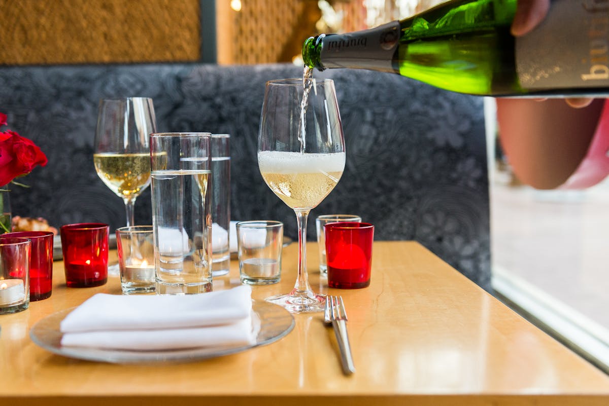 a person sitting at a table with wine glasses