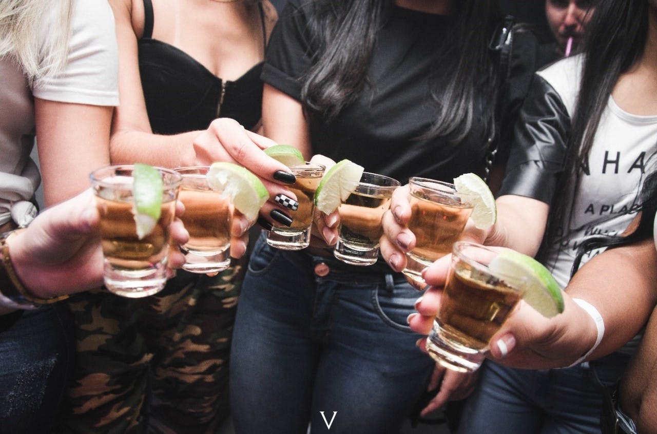 a couple of people are drinking from a shot glass