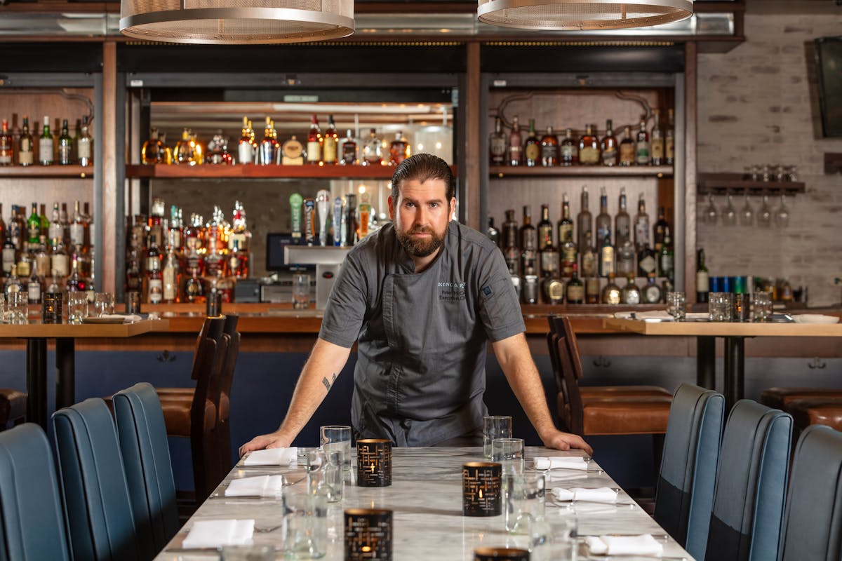 a man sitting at a table with wine glasses in front of a store