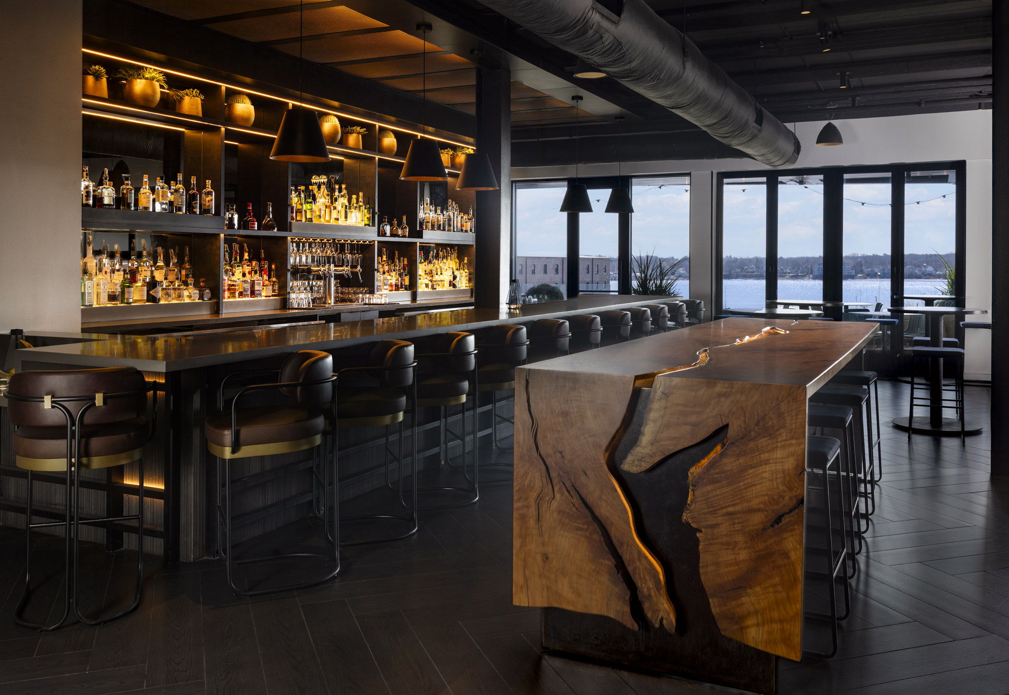 a bar with a wooden table and shelves with bottles