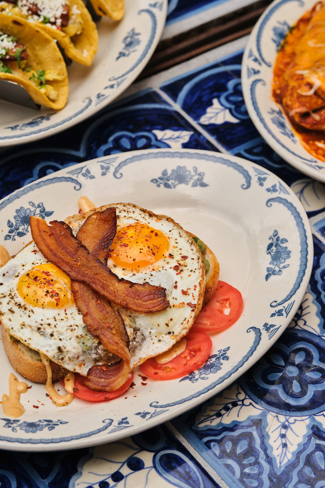 Brunch plate with sunny-side-up eggs, bacon and tomato on toast from the weekend brunch menu at Rocco's Tacos Orlando