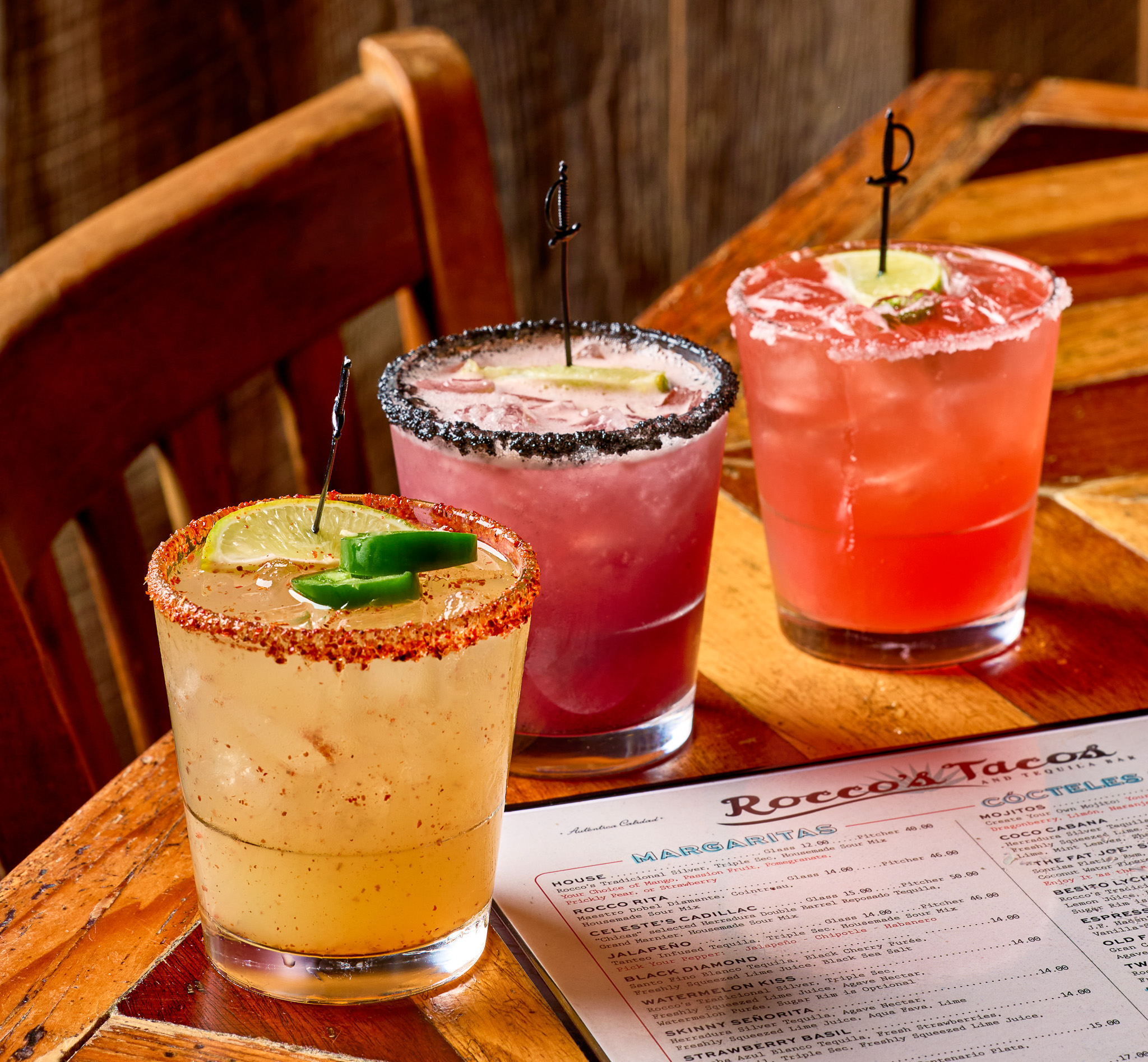 Three margaritas with salt rims beside a Rocco's Tacos happy hour menu at the Las Olas bar in Fort Lauderdale