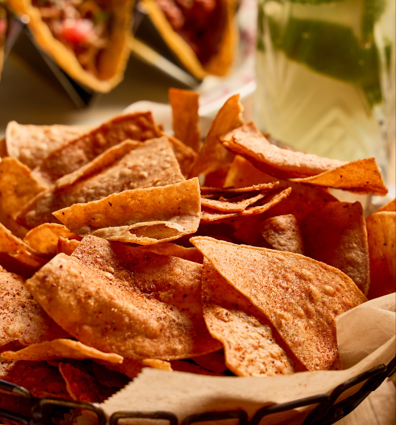 Basket of Rocco's chips dusted with Rocco's Spice, with tacos and a margarita in the background
