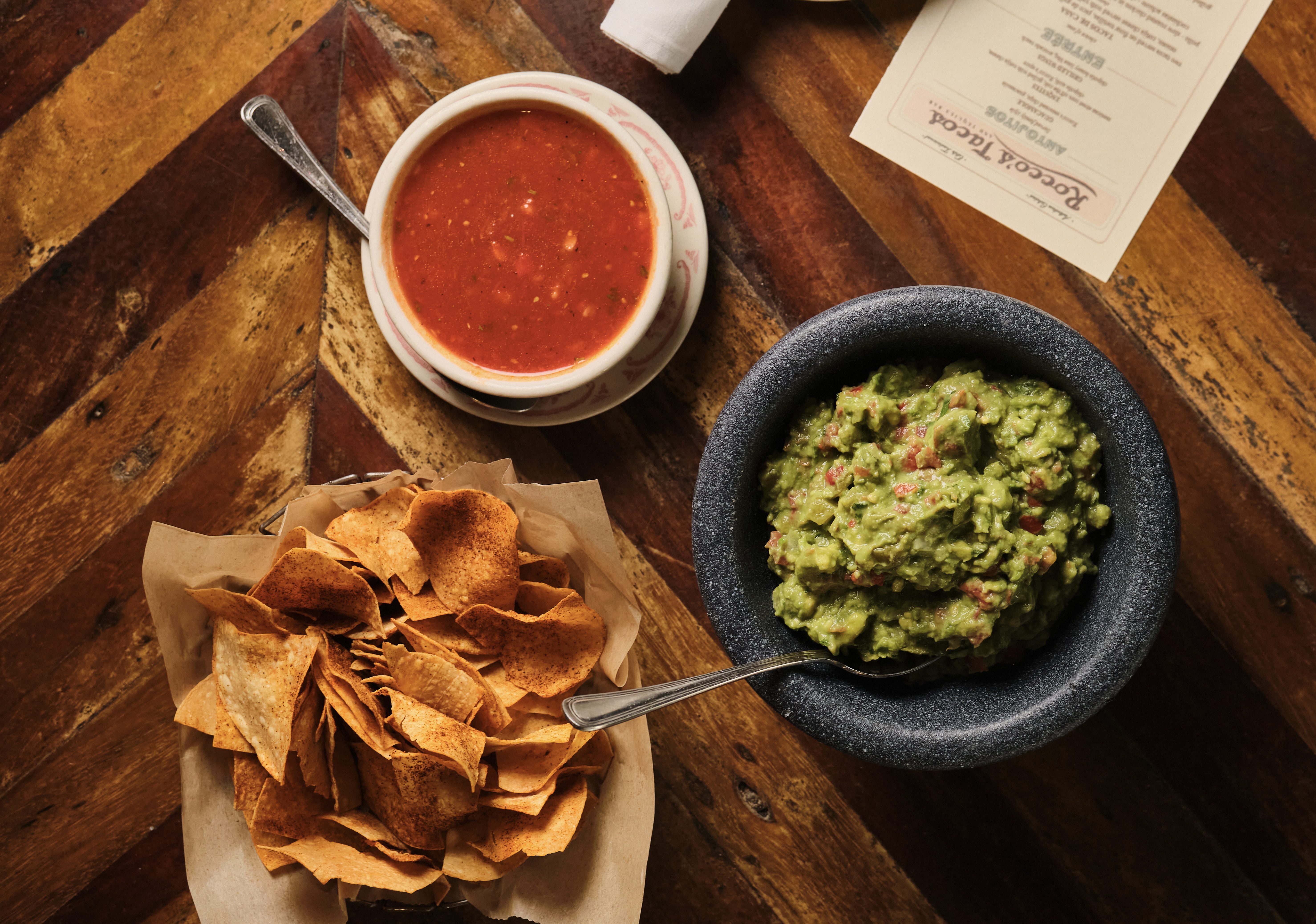 Fresh tableside guacamole in a molcajete with Rocco's chips and salsa roja at Rocco's Tacos