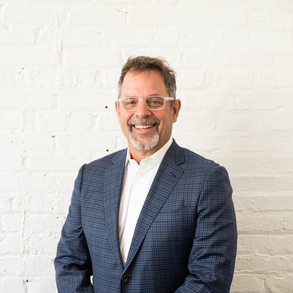 a man wearing a suit and tie smiling at the camera