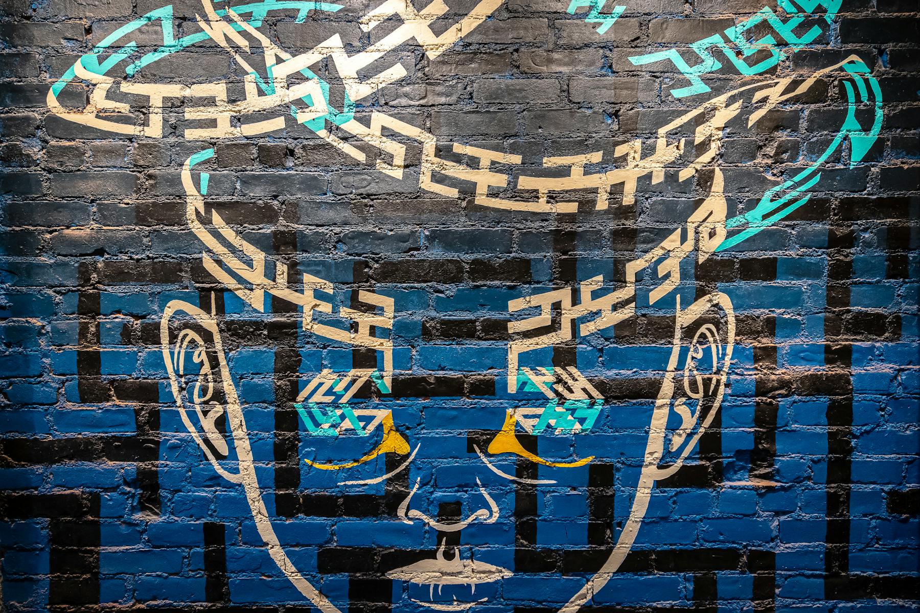 A brick wall painted blue and a gold face