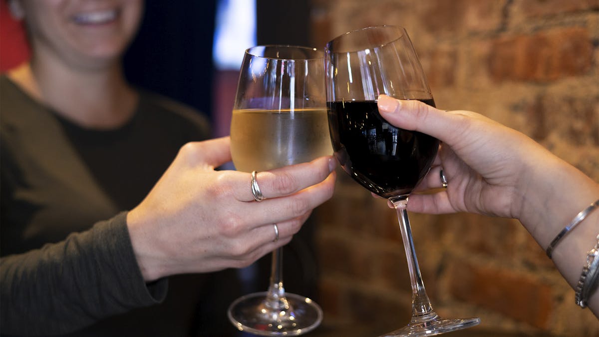 two people holding a glass of wine in their hands and cheering