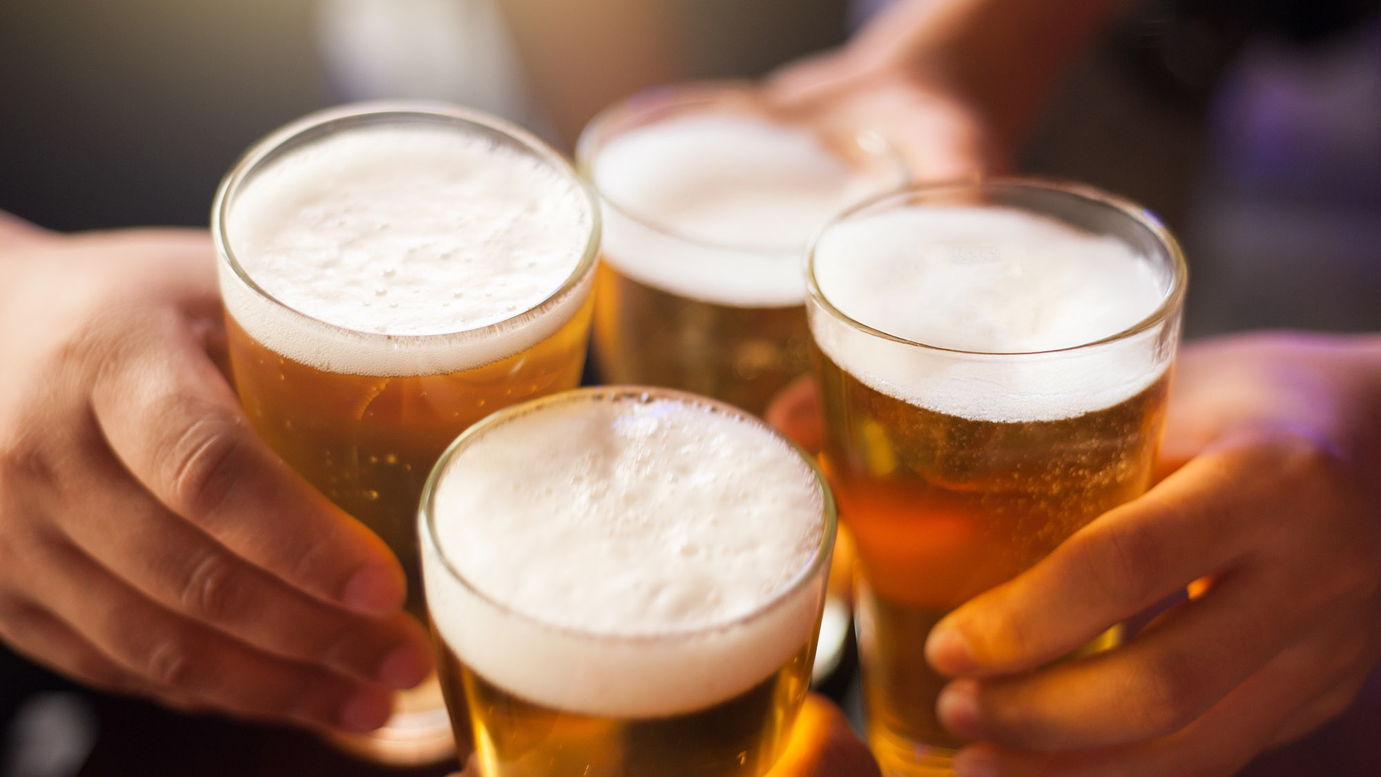 people cheersing with pints of beers