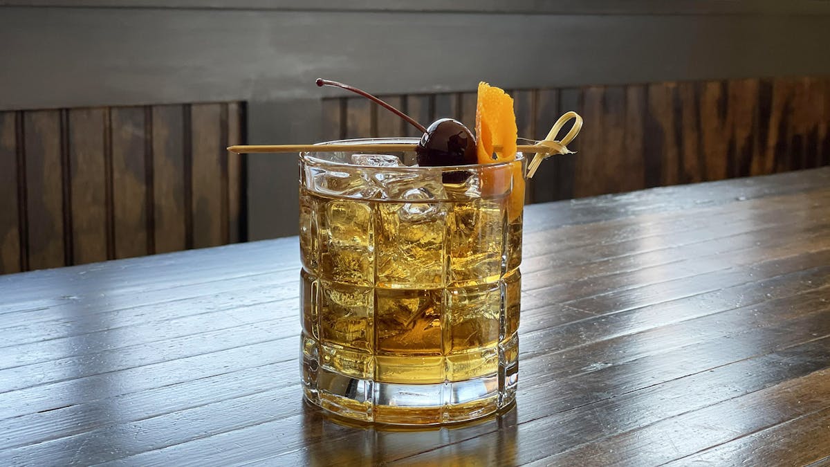 a glass of our Rivercrest Old Fashioned sitting on top of a wooden table