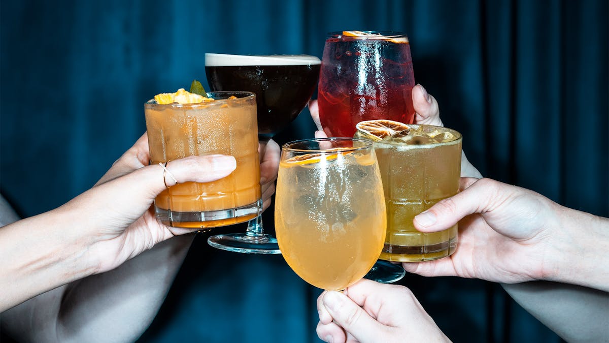 guests holding cocktails in their hands cheersing