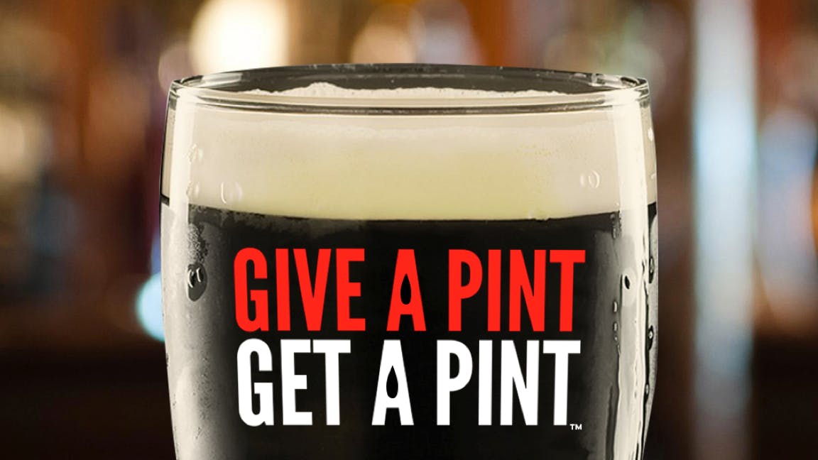 a close up of a beer glass with the words Give a Pint Get a Pint