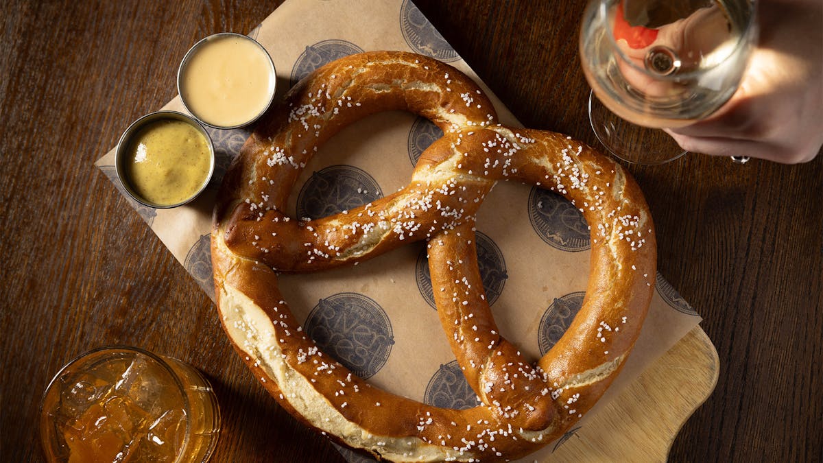 Rivercrest's Uber Bavarian Pretzel with IPA Mustard and beer cheese and wine and cocktail on a table