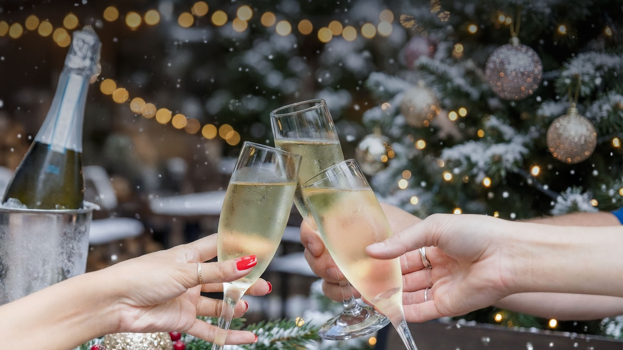 hands holding champagne glasses cheersing and ringing in the new year at Rivercrest with a Christmas tree in the background