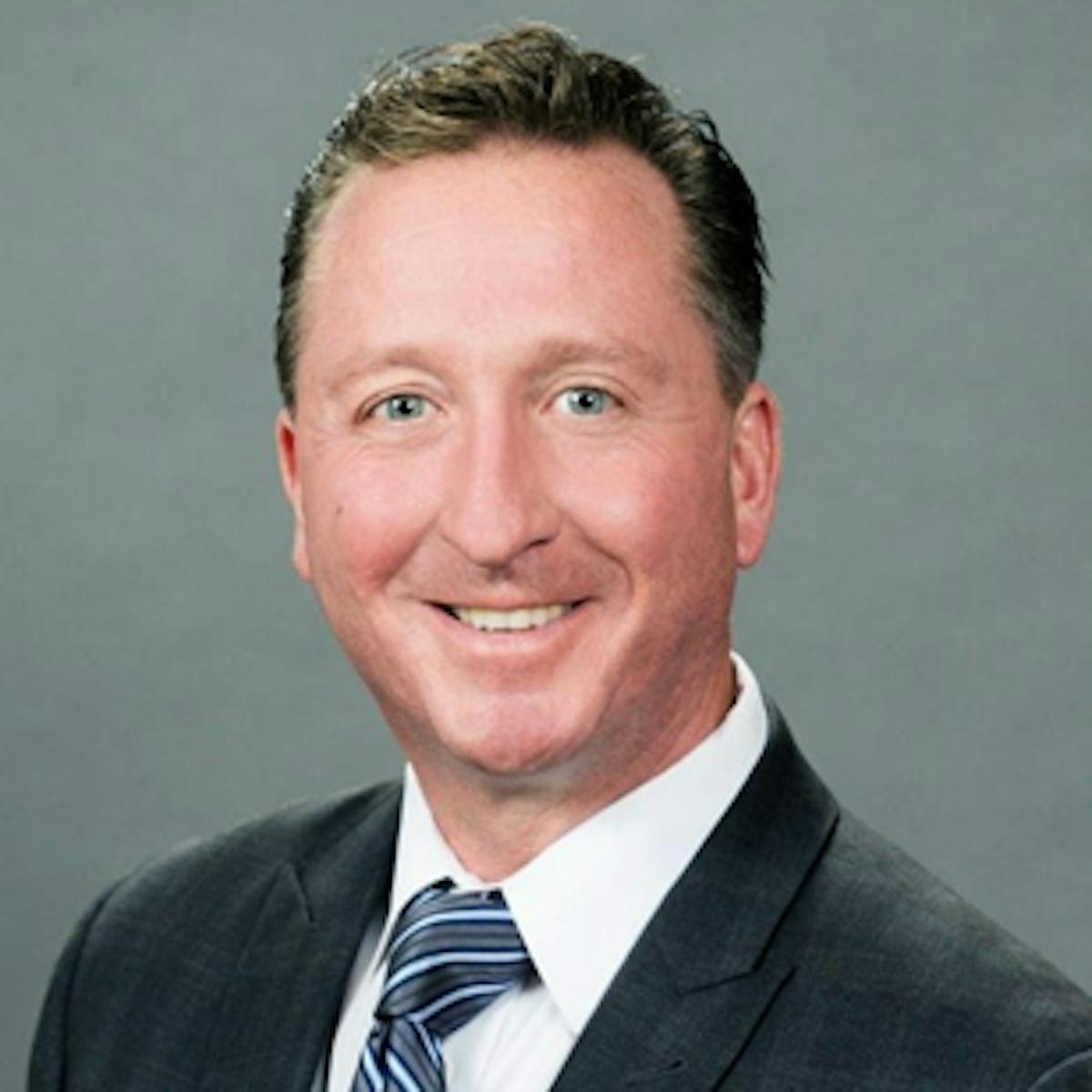 a man wearing a suit and tie smiling at the camera