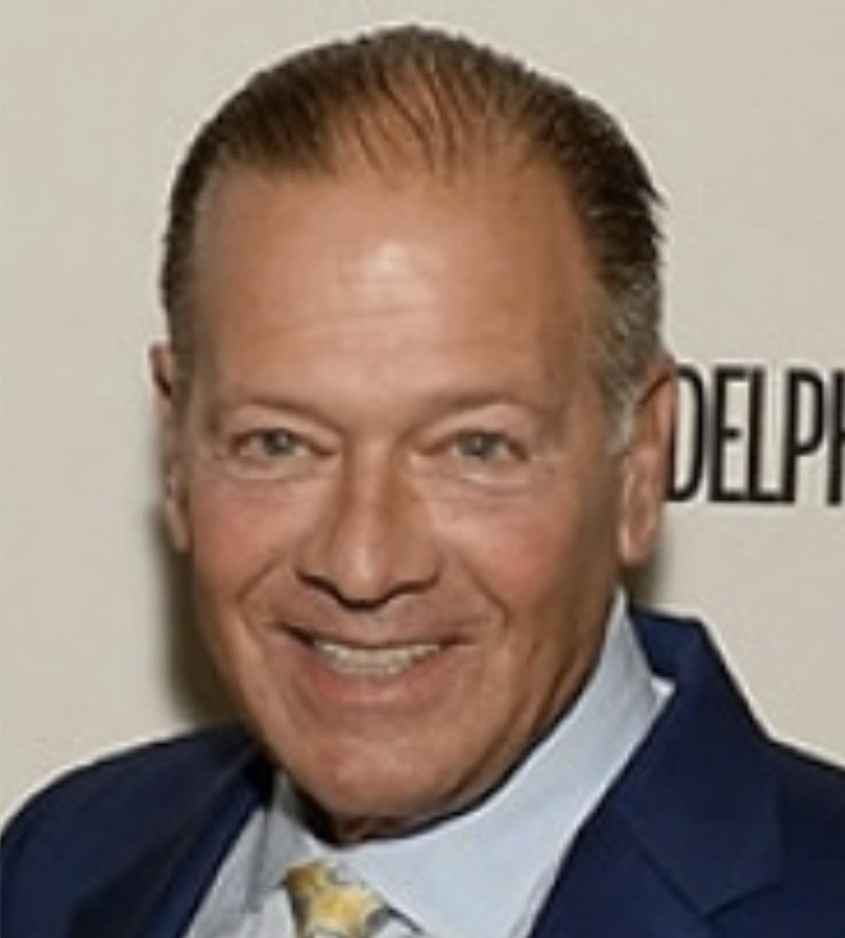 a man wearing a suit and tie smiling at the camera
