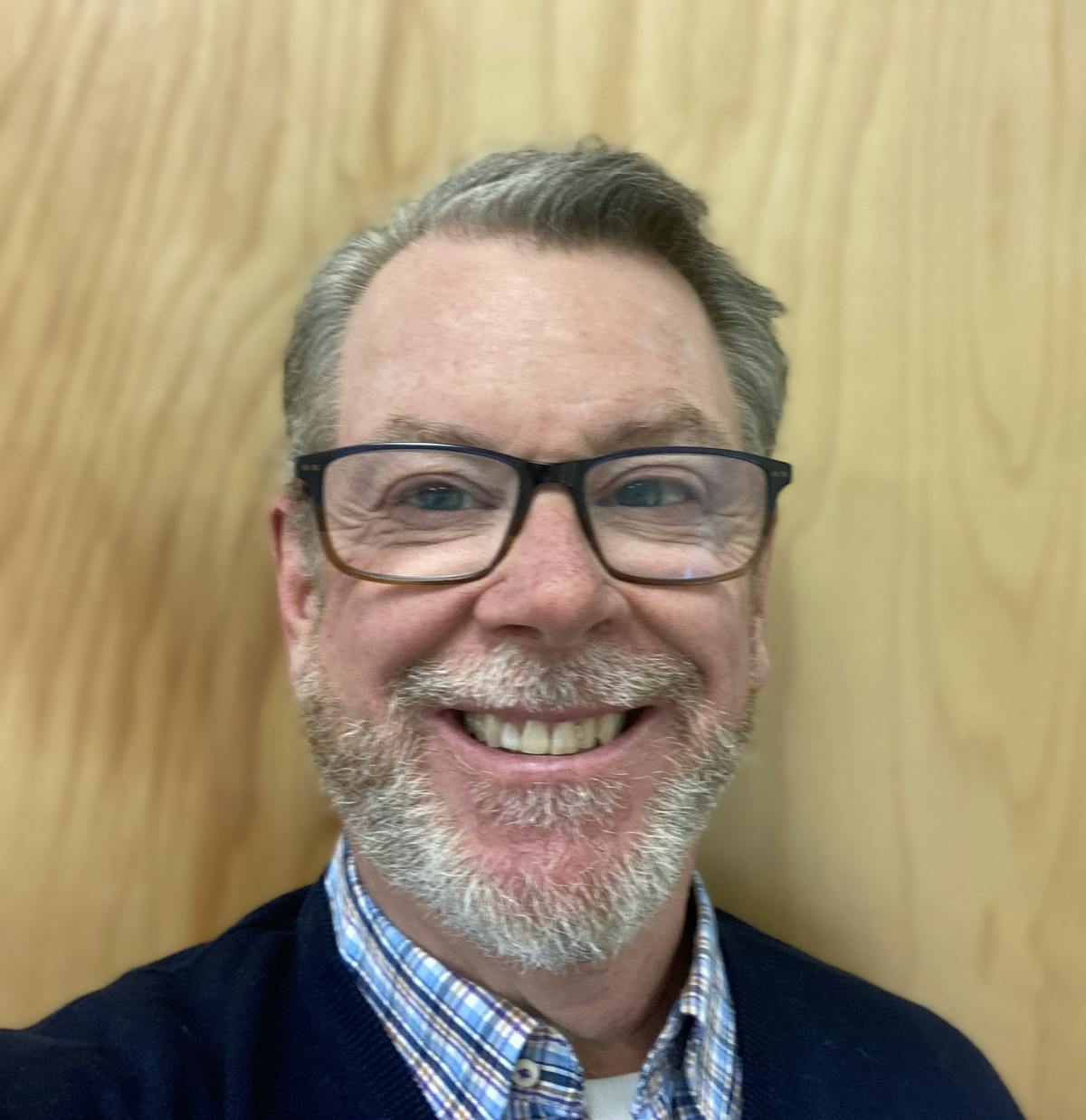 a man wearing glasses and smiling at the camera