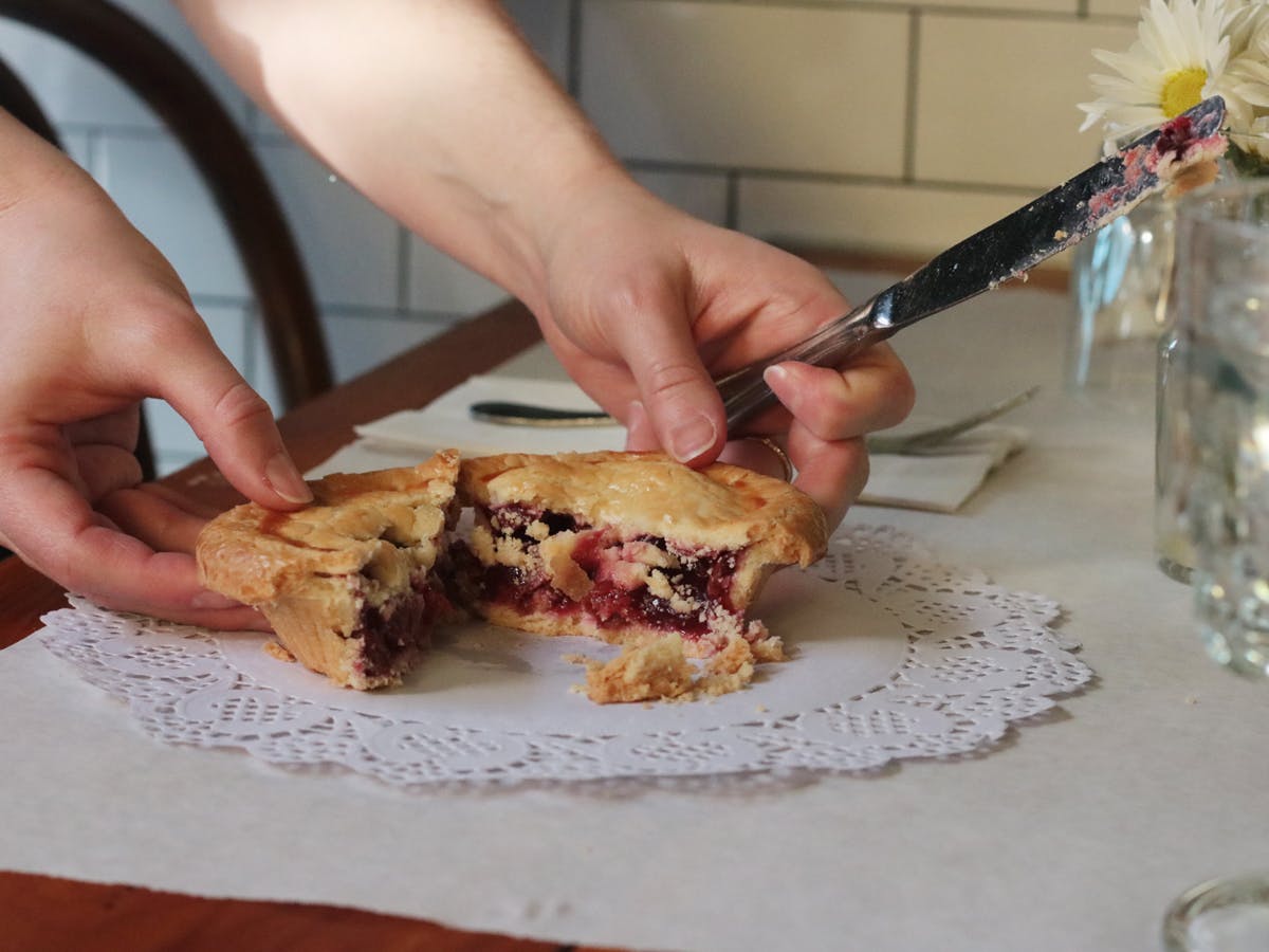 a woman cutting a piece of pizza