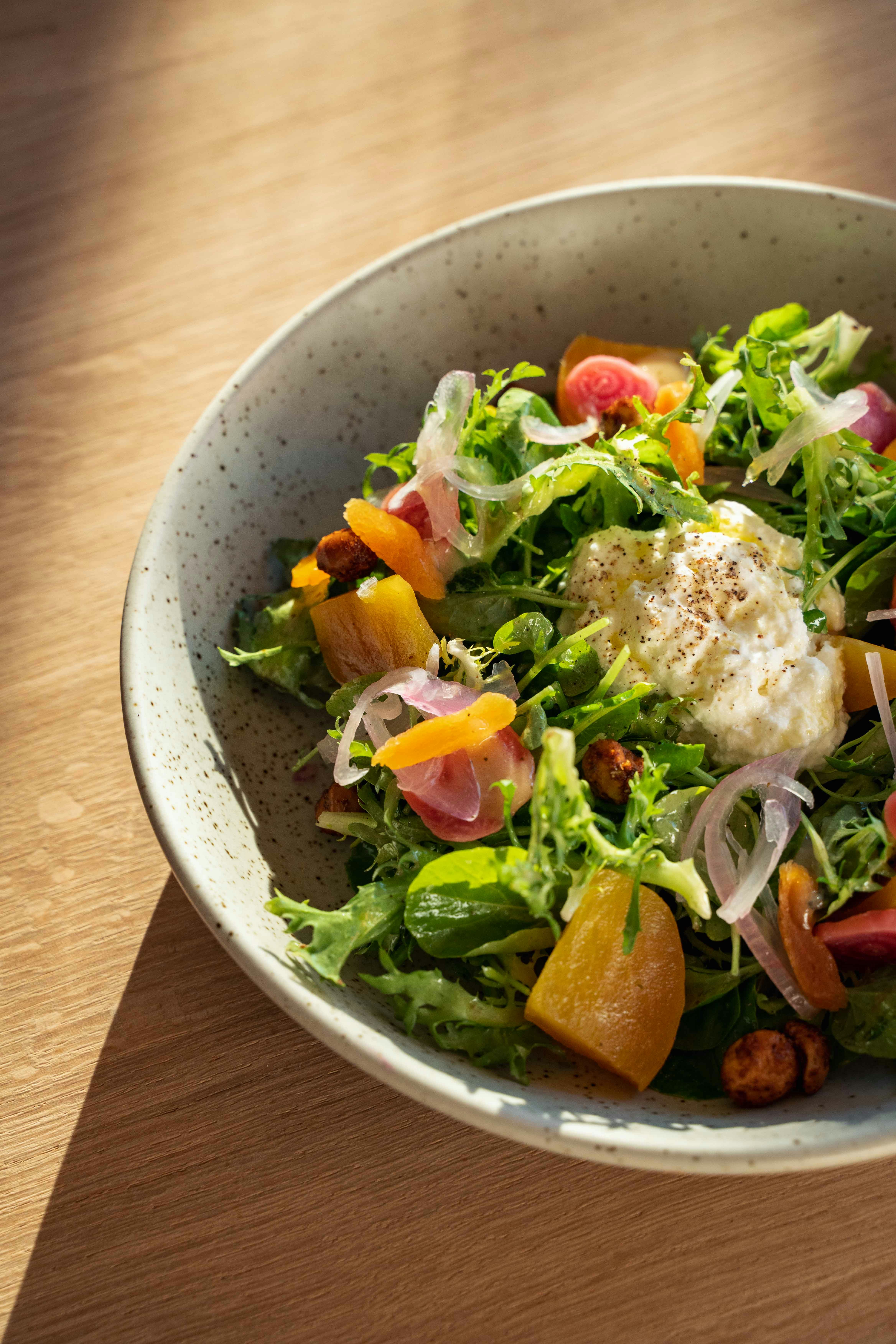a bowl of food on a plate on a wooden table