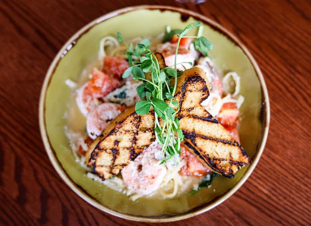 a bowl of food on a plate on a wooden table