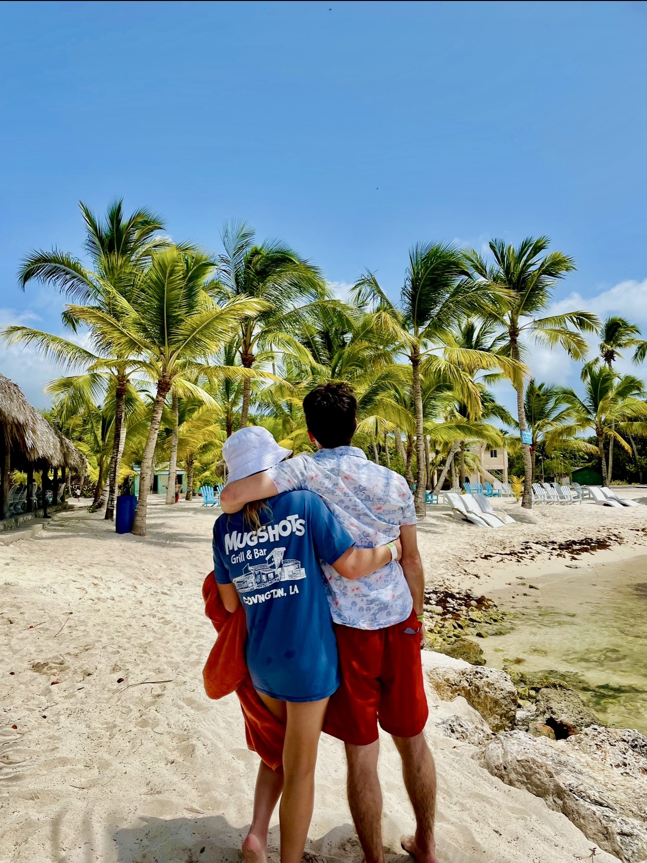 a man standing next to a palm tree on a beach