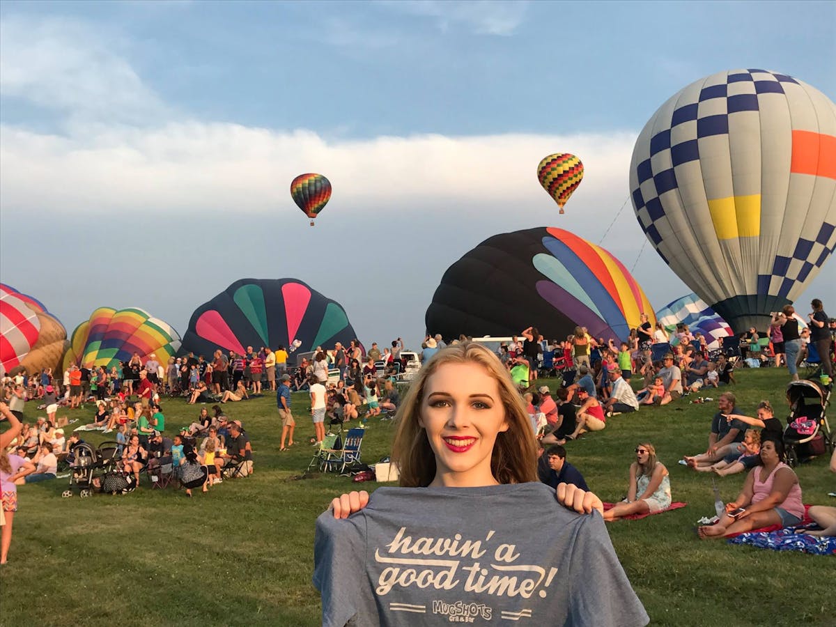 a person holding a shirt in front of hot air balloons