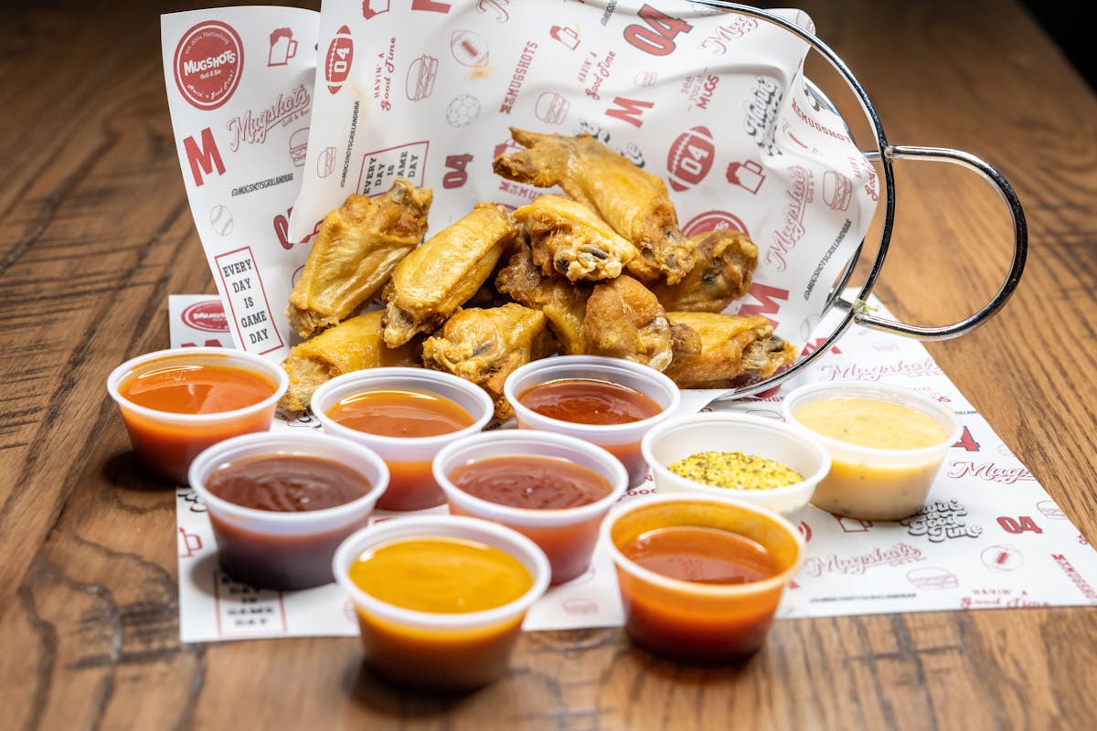 a basket of wings and sauces