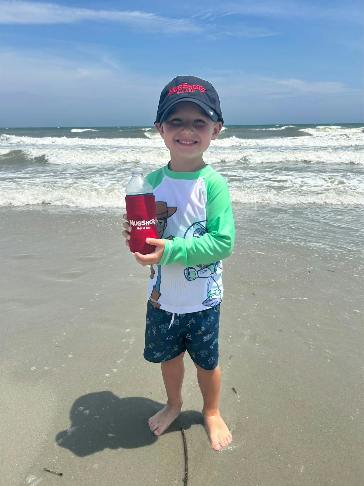 a little boy standing next to a body of water