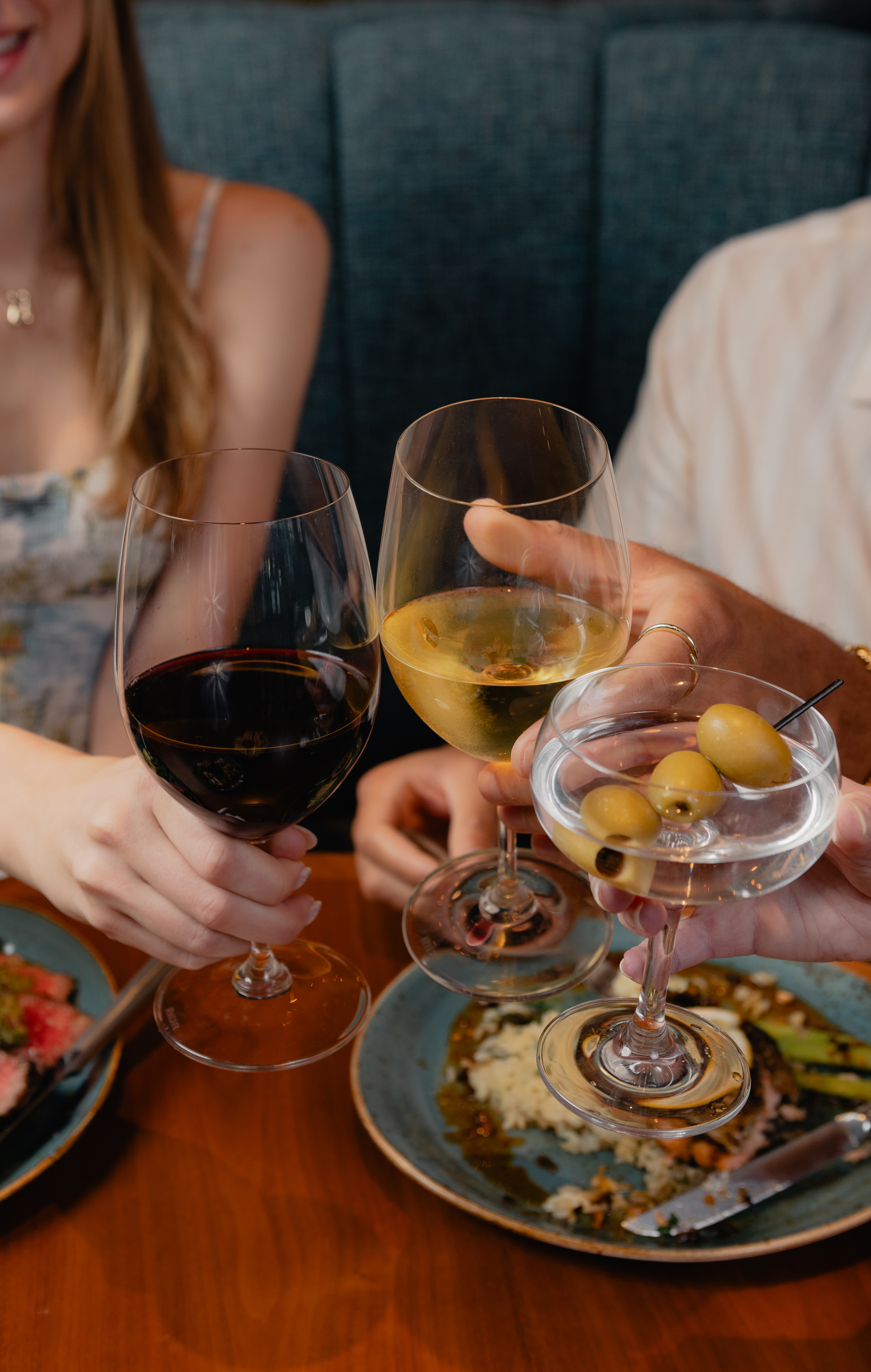 Guests toast with red wine, white wine, and an olive-garnished cocktail.