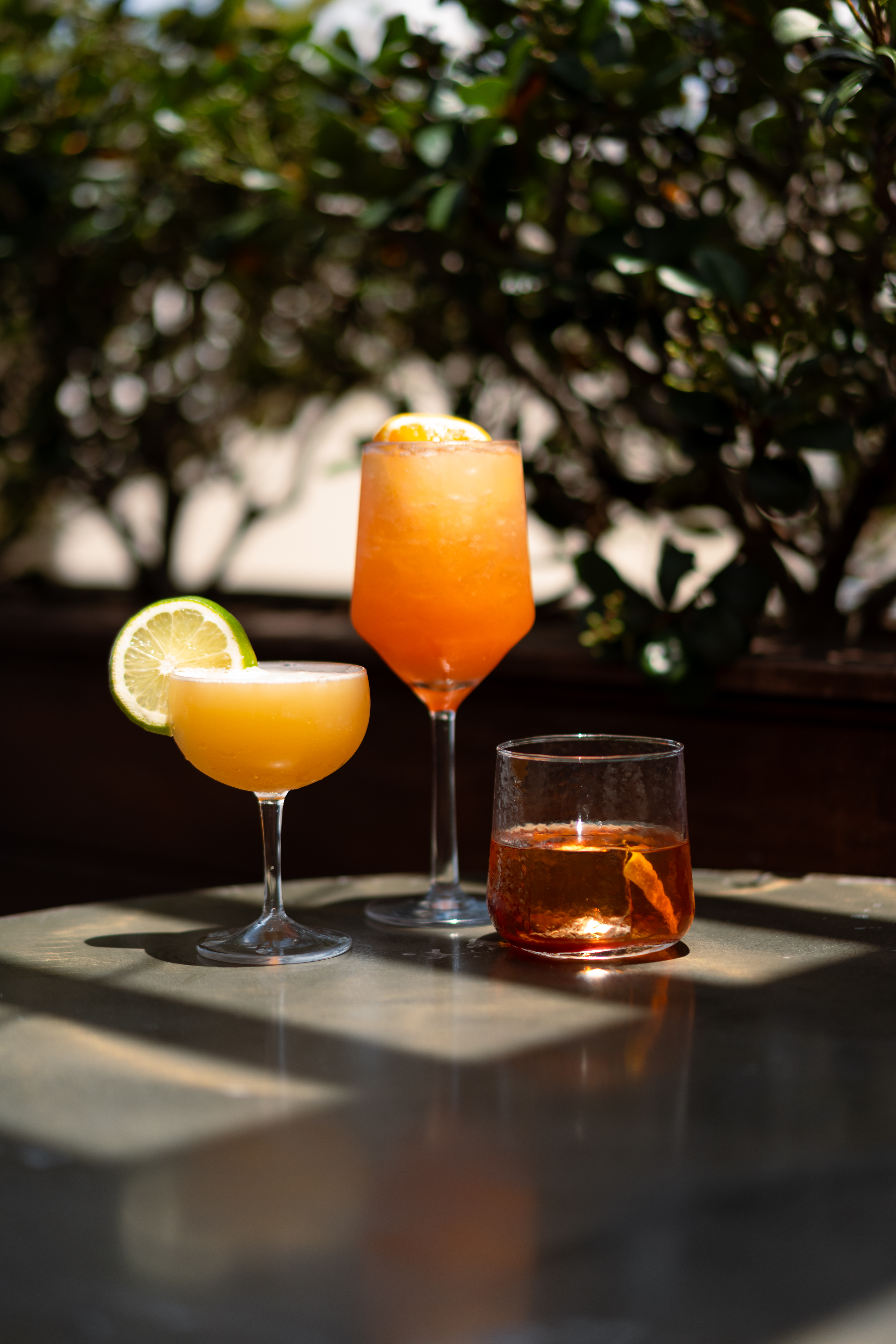 Assorted craft cocktails on a rooftop bar table with city backdrop.