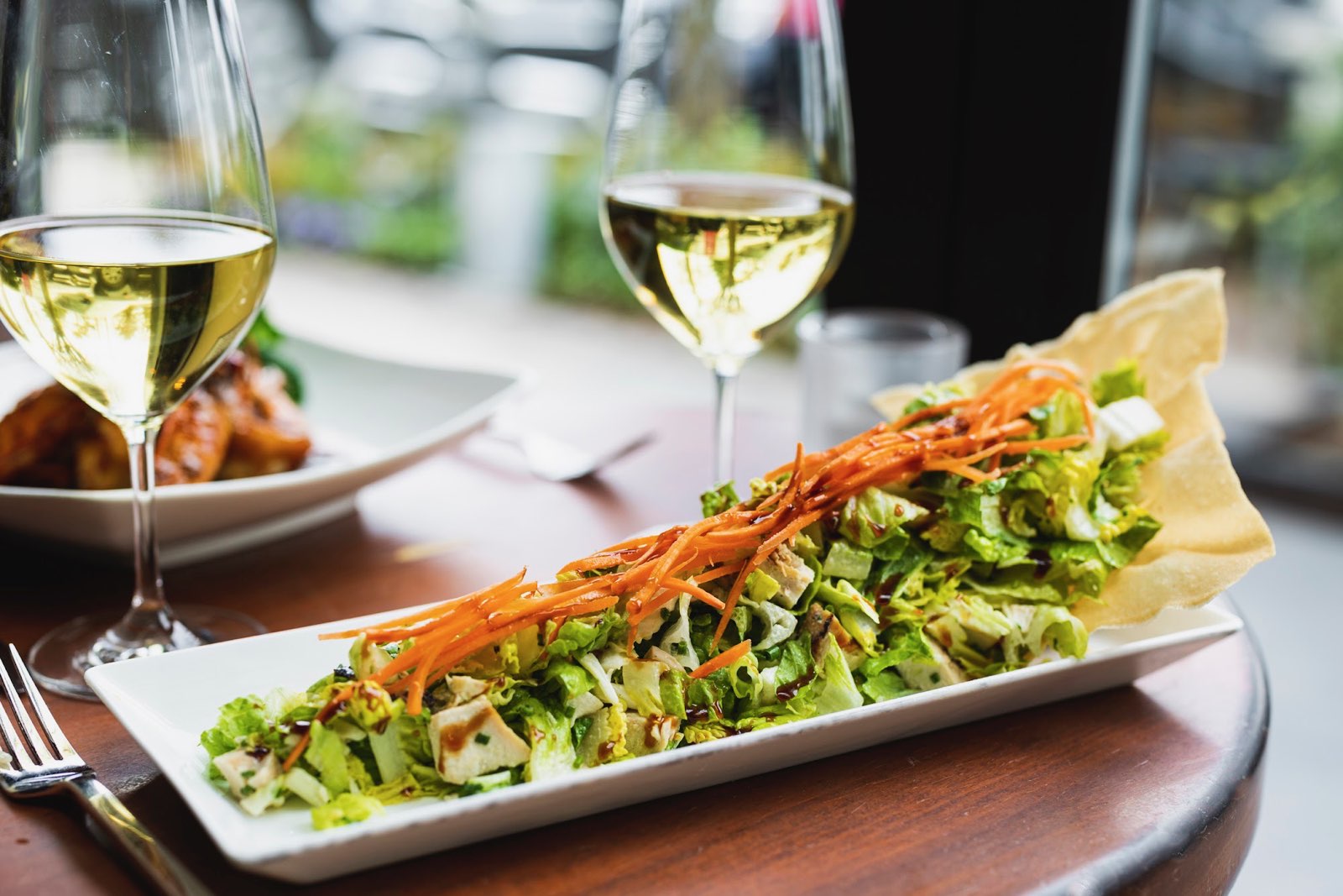 a close up of a plate of salad and a glass of wine
