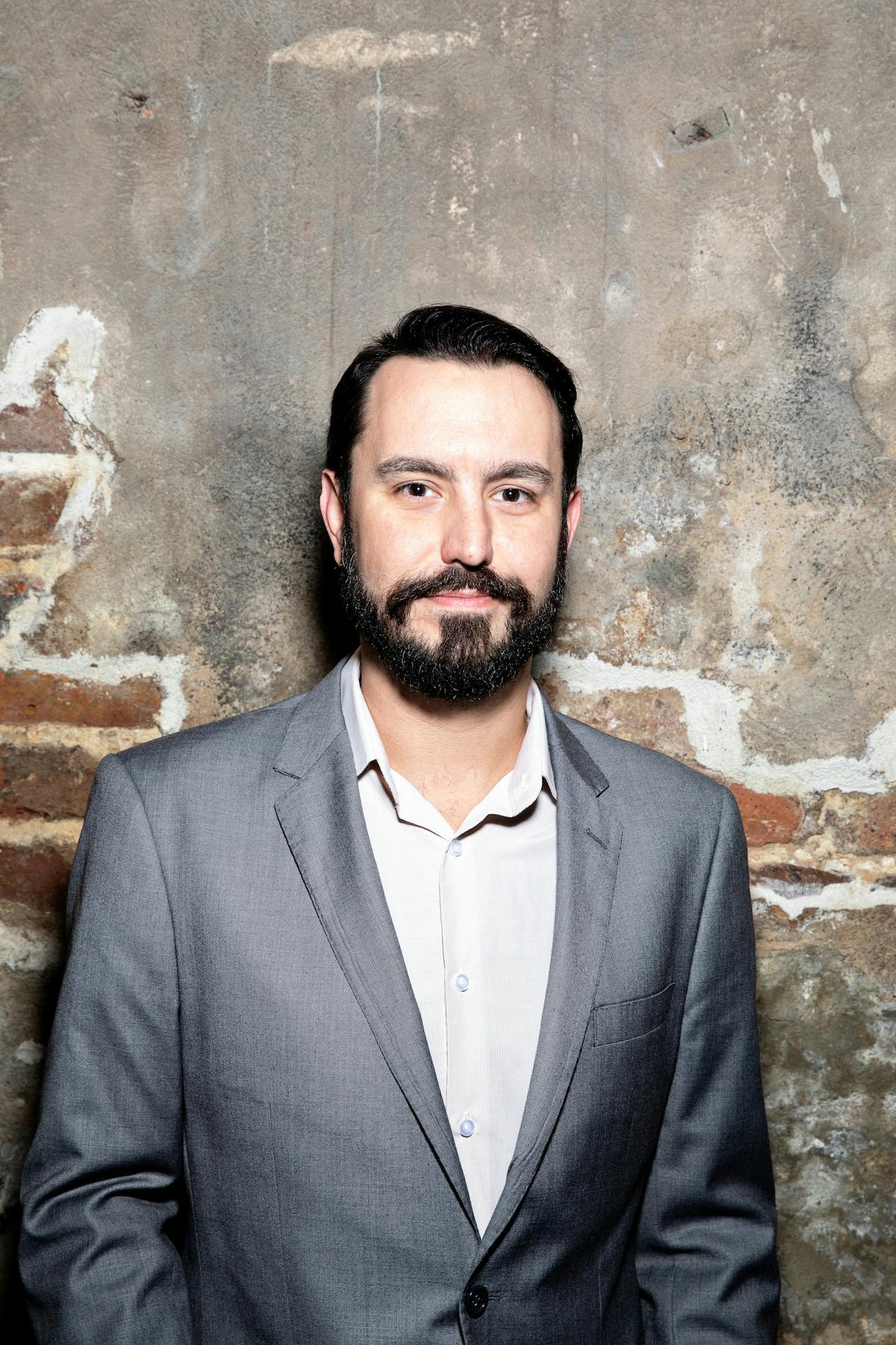 a man standing in front of a brick wall
