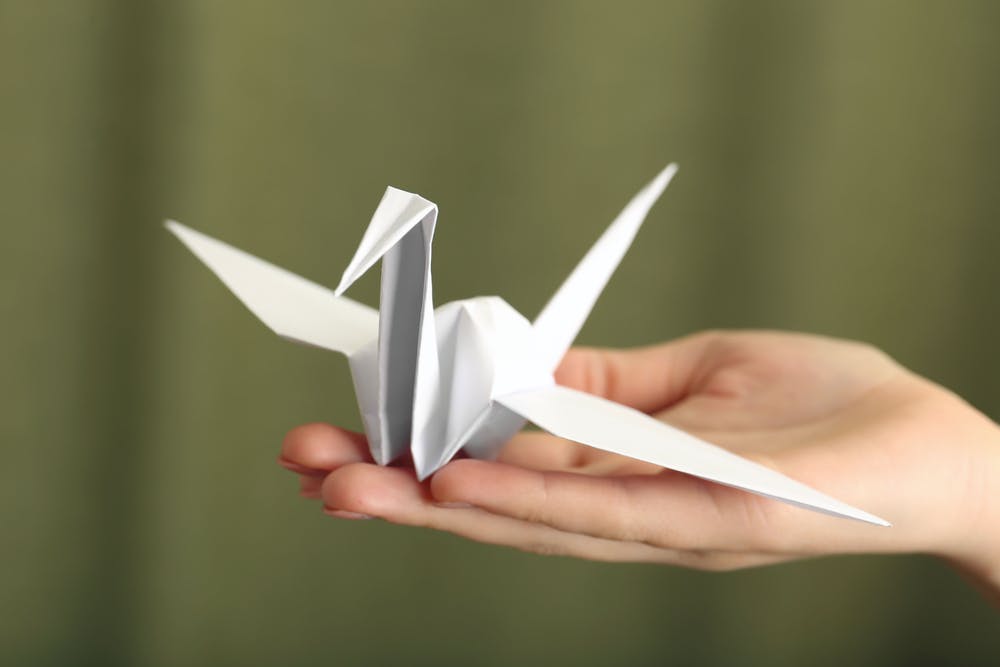 a hand holding an origami crane