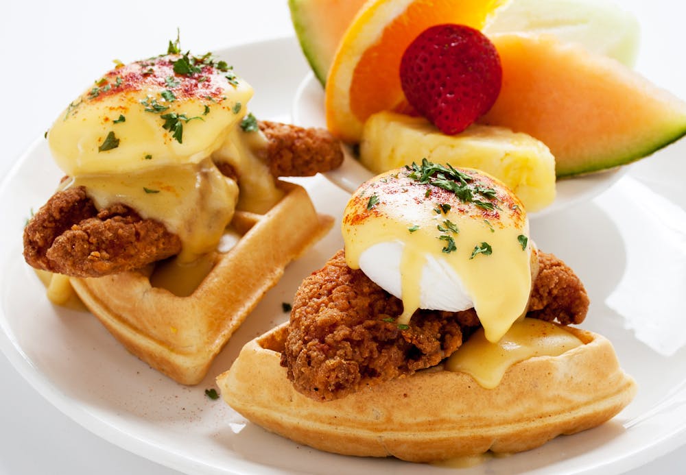 Omelets & Benedicts title. photo of bowl of assorted fruit and eggs benedicts on waffles