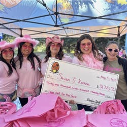 a group of people posing for a picture with a pink umbrella
